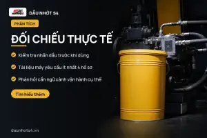 Đối chiếu thực tế: Thùng dầu màu vàng đặt cạnh một thiết bị máy móc tối màu.